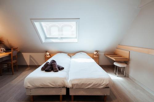 een slaapkamer met een bed met schoenen erop bij Hotel Brasserie De Beiaard in Torhout