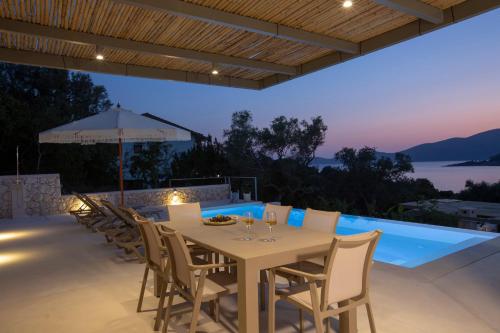 a dining table and chairs on a patio with a pool at Villa Sophia-Private Sea Access in Marantochori