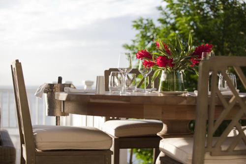 a wooden table with a vase of red flowers on it at Sugar Beach, A Viceroy Resort in Soufrière