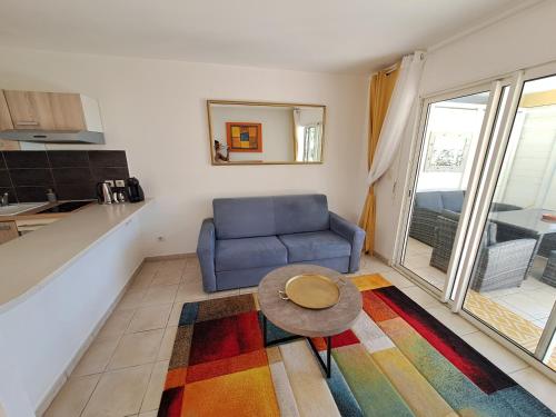 a living room with a blue couch and a table at RDC appartement en bord de mer au son des vagues in Le Moule