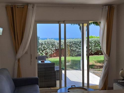 a living room with a sliding glass door to a patio at RDC appartement en bord de mer au son des vagues in Le Moule