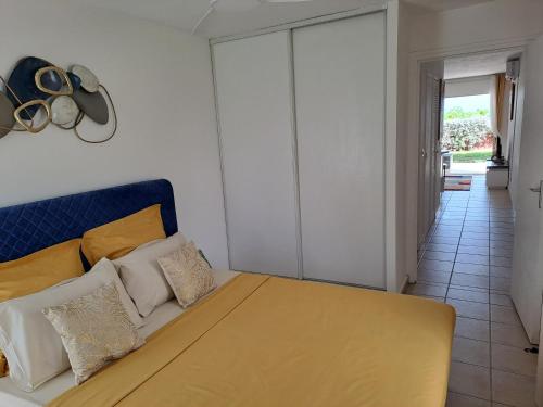 a bedroom with a bed with yellow and white pillows at RDC appartement en bord de mer au son des vagues in Le Moule