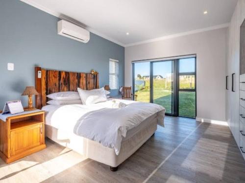 a bedroom with a white bed and a large window at The Halfway House @ Kingswood Golf Estate in George