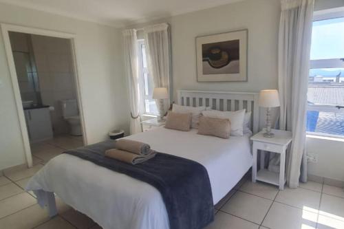 a white bedroom with a large white bed and a window at Point Village Accommodation - Linda in Mossel Bay