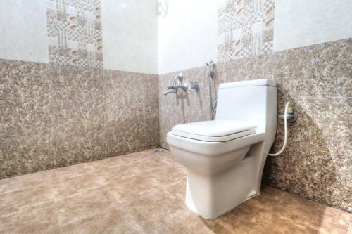 ein Bad mit einem WC und einer Mosaikwand in der Unterkunft Coorg Avani Holiday Inn in Madikeri