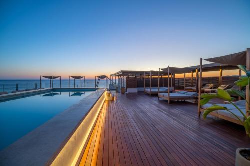 a pool on the deck of a building with the ocean at AKASHA Beach Hotel & Spa in Hersonissos