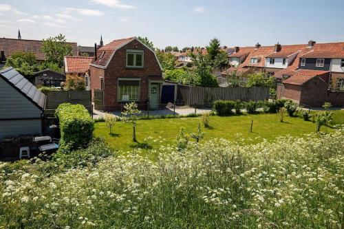 a yard with a house and a field of flowers at Vakantiehuisje Mies Rust en stilte aan het strand in Hoofdplaat