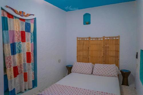 a small bedroom with a bed and a curtain at DAR DAUIA in Chefchaouene