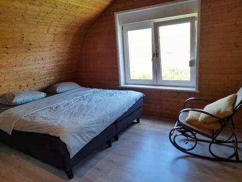 a bedroom with a bed and a chair and a window at Vakantiehuisje Mies Rust en stilte aan het strand in Hoofdplaat