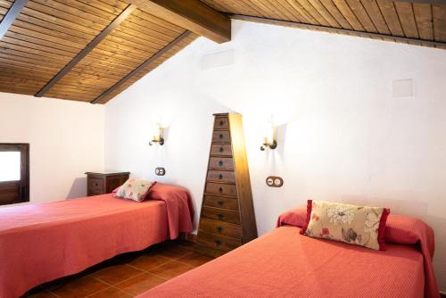 Villaviciosa de CórdobaにあるBungalows Camping Jimmy Jonesの白い壁と木製の天井が特徴の客室で、ベッド2台が備わります。