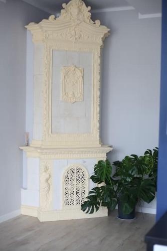 a white fireplace in a room with a plant at Authentic and Spacious flat in Jelenia Gora in Jelenia Góra