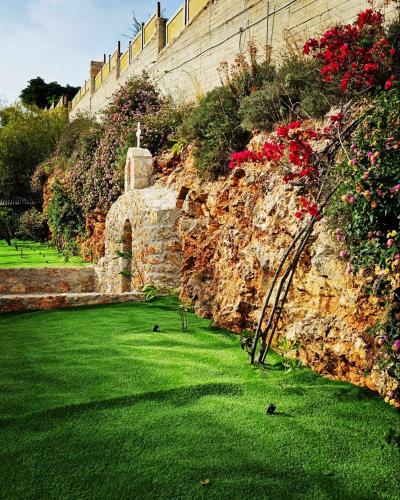 a garden with green grass and flowers and a stone wall at Nina Apartment in Chania Town
