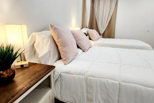 una camera da letto con un letto bianco e cuscini sopra di The Heart Of LA House a Los Angeles