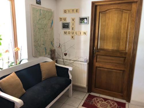 a living room with a couch and a wooden door at Gîte du vieux moulin in Ravilloles