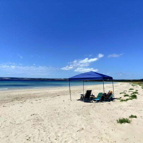 two chairs and a blue umbrella on a beach at Strandmarken in Island Beach