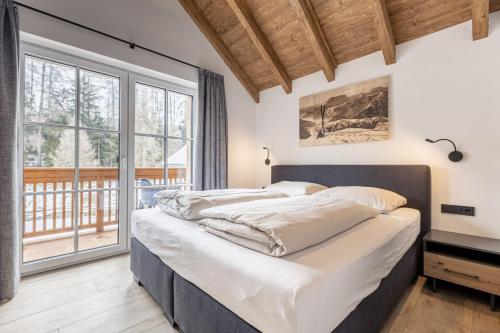a bedroom with two beds and a large window at AlpiNest Feriendorf Lungau in Mariapfarr