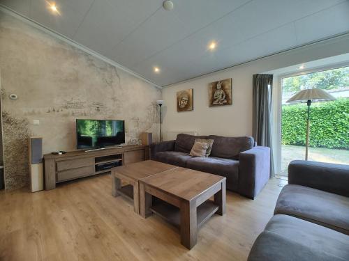 a living room with a couch and a flat screen tv at Limburg-Chalet in Susteren