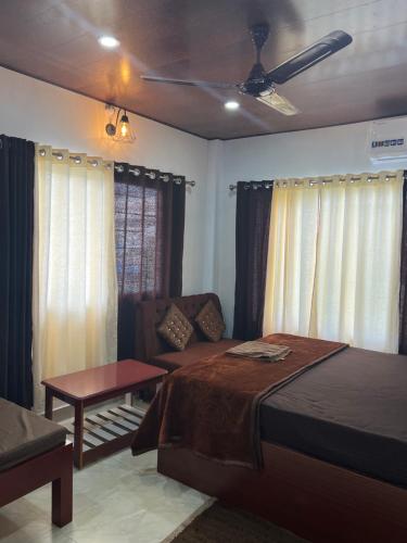 a bedroom with a bed and a couch and windows at J.J bed and breakfast in Port Blair
