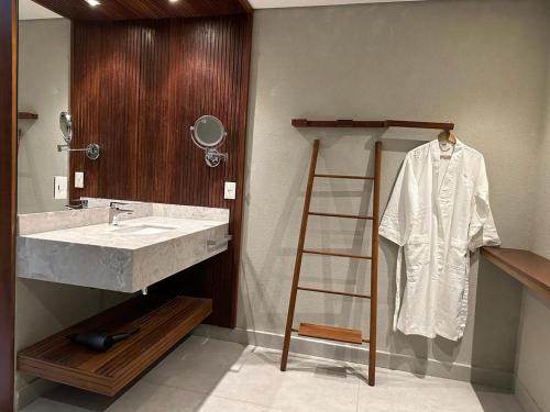 bagno con lavandino e accappatoio su una scala di Ilê de Pipa Resort a Pipa
