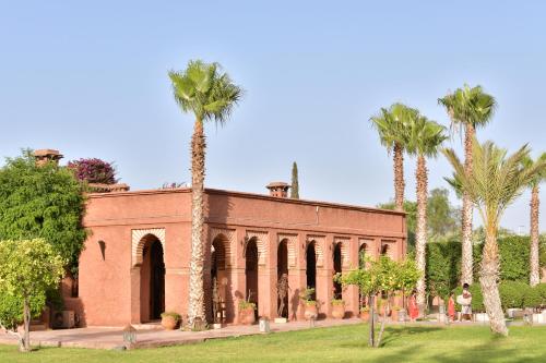 a brick building with palm trees in front of it at LES JARDINS DE MARRAKECH in Marrakech