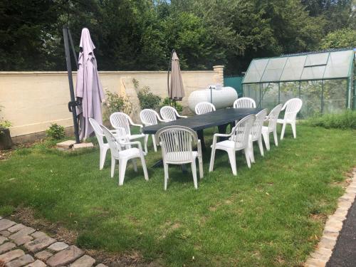 a long table and chairs with umbrellas in a yard at gite des 3 pleureuses in Saint-Riquier