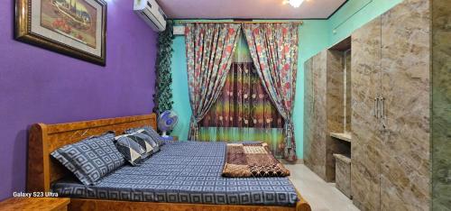 sypialnia z łóżkiem z fioletowymi ścianami i oknem w obiekcie UDUPI HOMESTAY - Garden Villa 5BHK w mieście Udupi