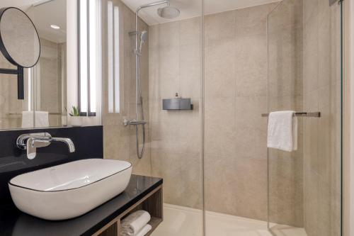 a bathroom with a sink and a glass shower at Citadines Kurfürstendamm Berlin in Berlin