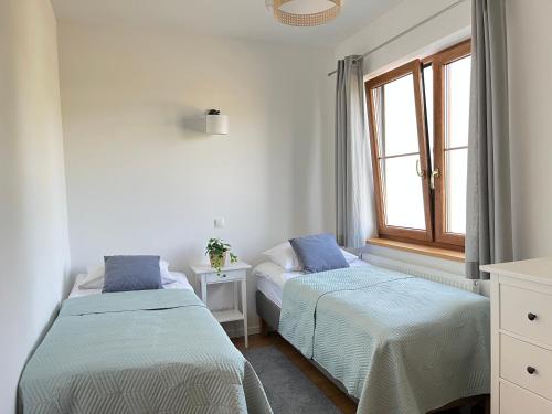 dwa łóżka w pokoju z oknem w obiekcie Apartament z ogrodem w Sarbinowie