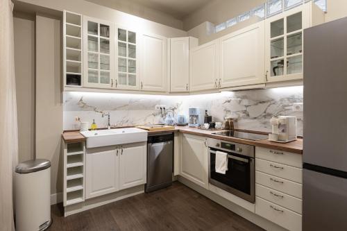 een keuken met witte kasten en een spoelbak bij Primavera Seafront apt by halu! next to White Tower in Thessaloniki