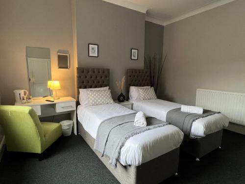 a bedroom with two beds and a desk and a chair at Alexander Hotel Whitley Bay in Whitley Bay