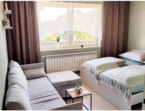 a bedroom with two beds and a couch and a window at Pokoje goscinne u Brody in Międzybrodzie Żywieckie