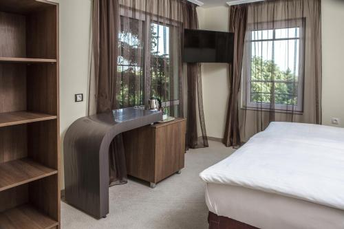 a bedroom with a bed and a desk and windows at Hotel Duchess in Varna City