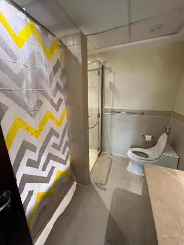 uma casa de banho com um WC branco e uma parede amarela e branca em بِيُوتات الرّفآه - أناقة المرينا em King Abdullah Economic City