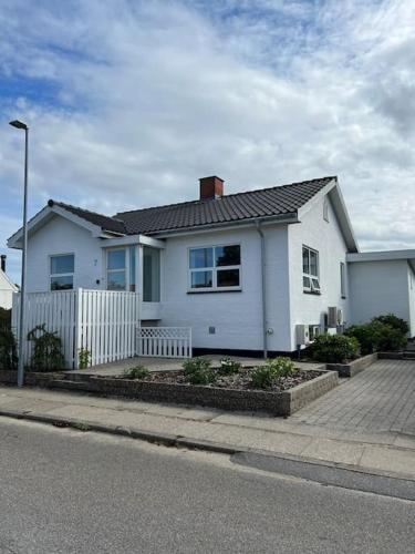 una casa blanca con una valla delante en Bjergby Sønderbo feriehus en Bjergby