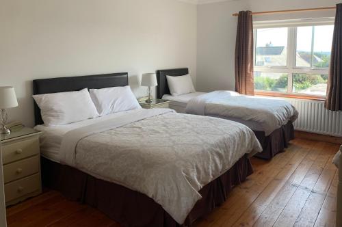 two beds in a hotel room with a window at Quay House in Wexford