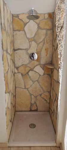 a shower in a bathroom with a stone wall at Villasimius Appartamento "Il Ginepro" in Villasimius