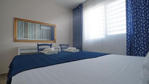 1 dormitorio con 1 cama con cortinas azules y ventana en Blue Eye Apartment, en Sarandë