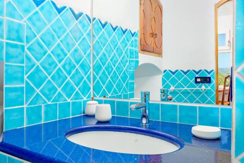 a blue tiled bathroom with a sink and a mirror at Esclusive House [Costa Smeralda Baia Sardinia ] Monica House in Baja Sardinia