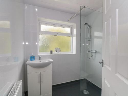 a white bathroom with a sink and a shower at Coed Bach in Prestatyn