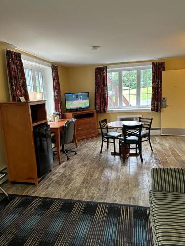 a living room with a table and chairs and a television at Swiss Chalets Village Inn in North Conway