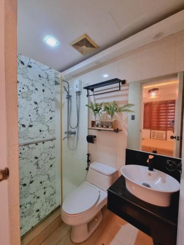 uma casa de banho com um chuveiro, um WC e um lavatório. em Modern Minimalist Condo near Airport em Manila