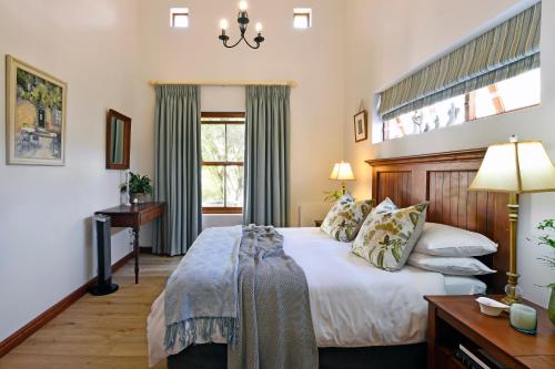 Un dormitorio con una cama y un escritorio y una ventana. en Petit Plaisir is a romantic self-catering cottage on the side of the village no1, en Franschhoek
