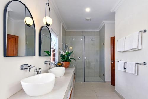 Un baño con dos lavabos y una ducha. en Petit Plaisir is a romantic self-catering cottage on the side of the village no1, en Franschhoek
