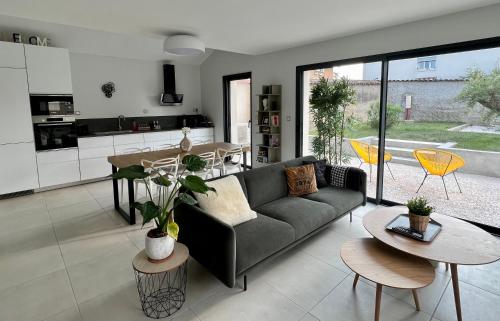 - un salon et une cuisine avec un canapé et des tables dans l'établissement Villa Gaïa - 2 suites lits King size et salles de bain privatives - parking privé - 10 minutes Eurexpo - Aéroport - Groupama Stadium, à Genas