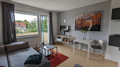 ein Wohnzimmer mit einem Sofa, einem Tisch und einem Fenster in der Unterkunft Ferienwohnung Bad Vilbel in Bad Vilbel