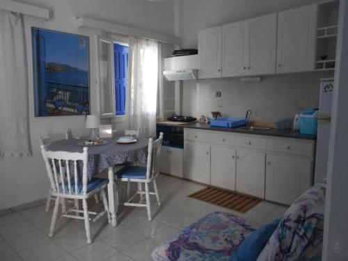 a kitchen with a table and chairs and a kitchen with white cabinets at Meltemia Studio Samos No6 Pefkos in Votsalákia