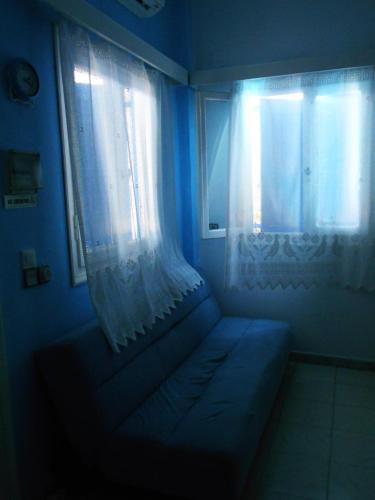 a blue room with a window with a couch and a curtain at Meltemia Studio Samos No6 Pefkos in Votsalákia