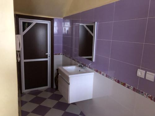 Appartement Meublé à Louer 95m2 في تزنيت: حمام أرجواني مع حوض ومرآة