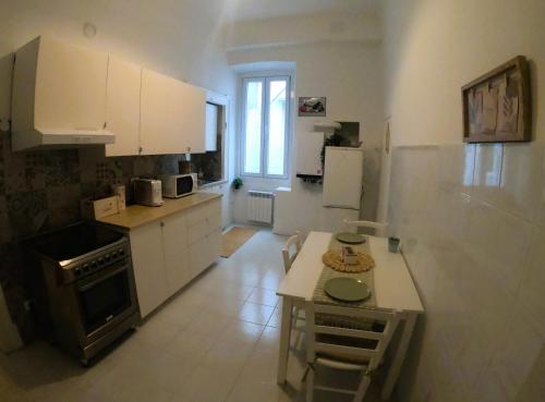 a kitchen with white cabinets and a table in it at Casa Vacanze Trieste Piace in Trieste