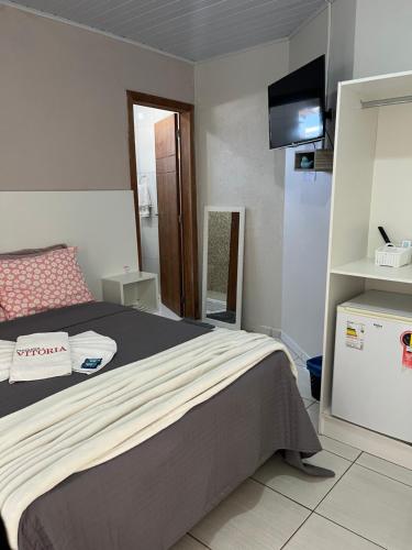 um quarto com uma cama e uma televisão em Pousada Vitória em Penha